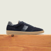 Men's navy European suede lace-up sneaker with beige rubber sole on a wooden platform.