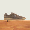 Men's taupe European suede lace-up sneaker with beige rubber sole on a wooden platform.