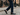 Man walking in city cobblestone street wearing men's black Italian leather lug sole penny loafer dress shoes.